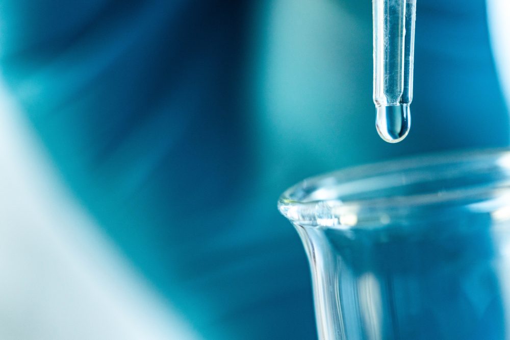 Extreme close up of a drop of oil falling in a beaker.
